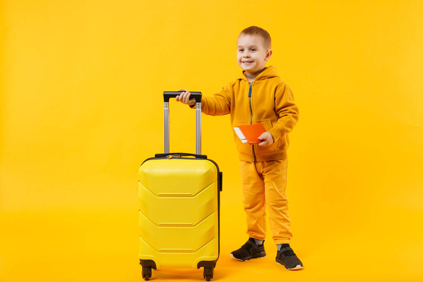 Piccolo viaggiatore turista bambino ragazzo 3-4 anni isolato su giallo arancio parete sfondo studio. Passeggero che viaggia all'estero per viaggiare durante il fine settimana fuga. Concetto di volo aereo. Spazio di copia Mockup
 - Foto, immagini