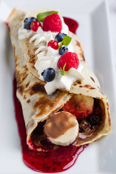 european pancakes, sweet crepe with topping on white long plate - Фото, изображение
