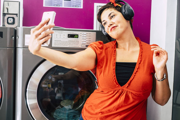Γυναίκα με τη χρήση smartphone στο κατάστημα mat αυτόματη υπηρεσία πλυντηρίου - Φωτογραφία, εικόνα