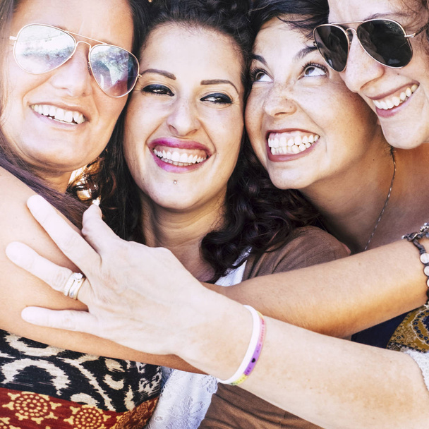 Primo piano ritratto con quattro giovani donne caucasiche con i volti uniti che si divertono molto insieme lanciando e sorridendo come pazzi - amicizia e felicità concetto di persone all'aperto - donne allegre che si abbracciano - Foto, immagini