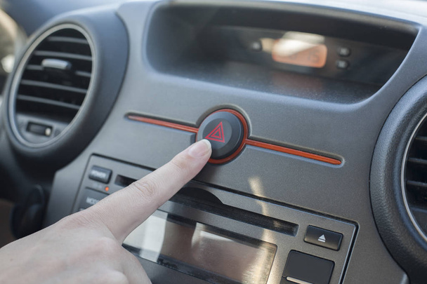 Женщина нажимает кнопку аварийного освещения. Вид изнутри автомобиля
 - Фото, изображение