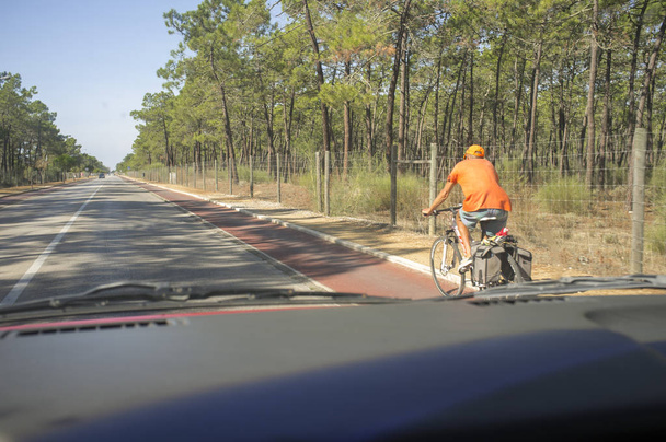 Vorsichtig fuhr er mit älteren Radfahrern auf dem Radweg an der Landstraße. Blick aus dem Inneren des Autos - Foto, Bild