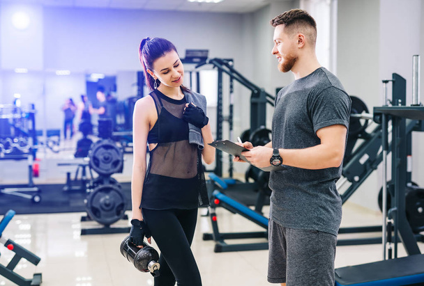Personal trainer and his female client standing together and discussing nutrition or training plan on clipboard. Healthy lifestyle, fitness concept - Valokuva, kuva