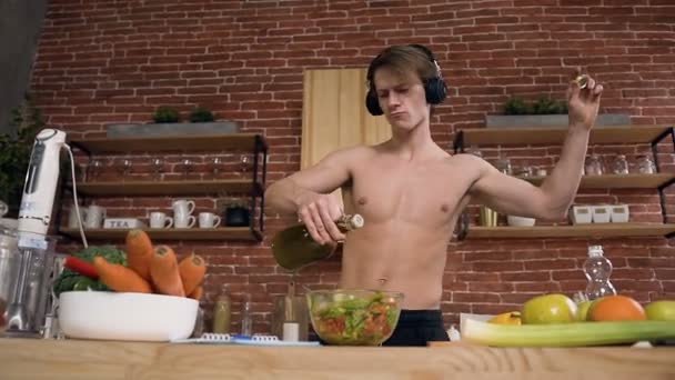 Attractive boy listening music in the headphone and dancing while cooking. - Video