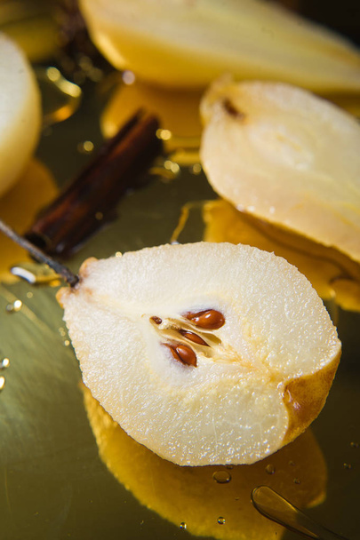 Sliced pear poached on a gold tray, cooked on white wine. Black background, side view, close up - Фото, зображення