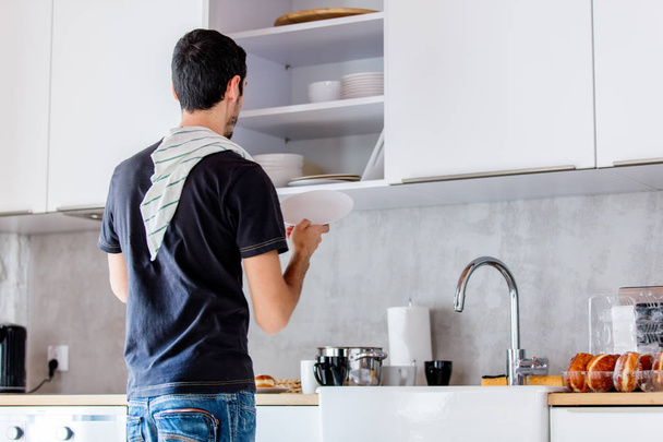 Junger Mann in schwarzem Hemd kocht zu Hause in Küche. - Foto, Bild
