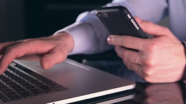 Der kaukasische Geschäftsmann arbeitet online mit seinem Laptop und Smartphone. Synchronisierung mobiler Geräte - Filmmaterial, Video