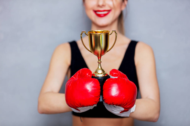 junge Frau in Boxhandschuhen mit goldenem Pokal - Foto, Bild