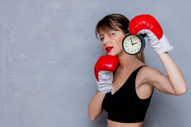 Молода жінка в боксерських рукавичках з будильником
 - Фото, зображення
