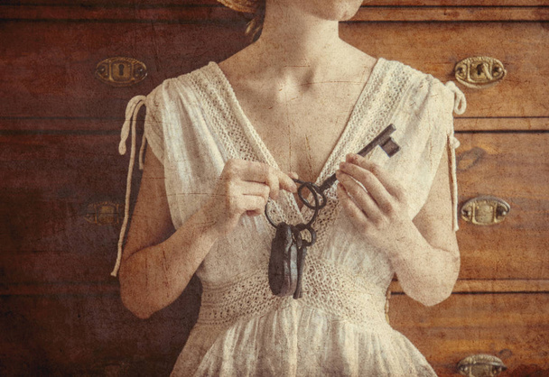 Жінка тримає старий ключ і замикається в руках
 - Фото, зображення