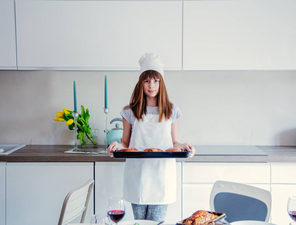 Młoda dziewczyna w kuchni ubrania z Pączki pieczone w kuchni. - Zdjęcie, obraz