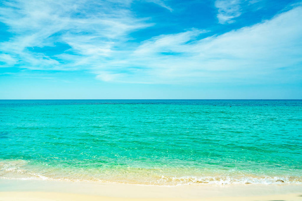 Playa de arena dorada junto al mar con agua de mar verde esmeralda y cielo azul y nubes blancas. Vacaciones de verano en concepto de playa paraíso tropical. Onda de agua salpicada en la playa de arena. Vibraciones de verano.  - Foto, imagen