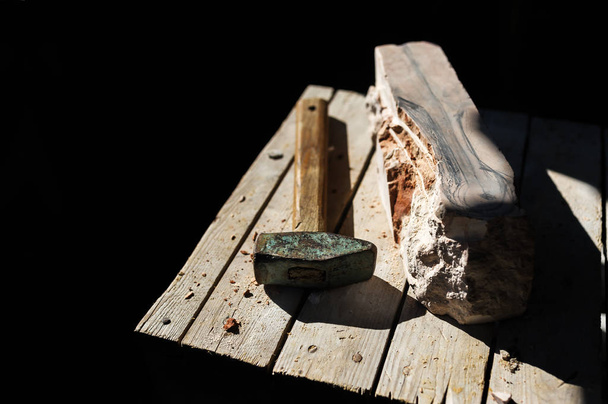 Молоток и большой камень на деревянном стуле на черном фоне. Концепция строительства
 - Фото, изображение