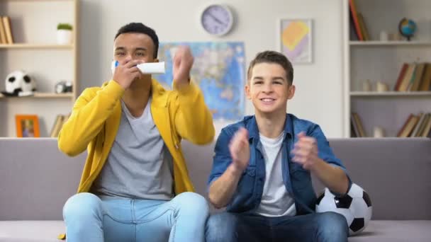 Teenage soccer fans cheering for national football team at home blowing vuvuzela - Video, Çekim