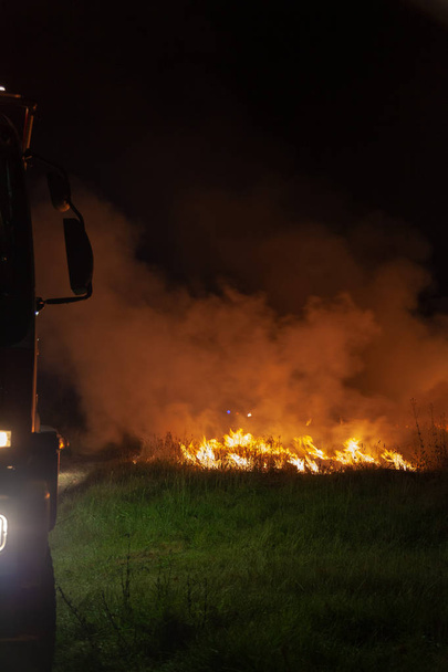 Camion de pompiers au feu arrière et éteindre une herbe de feu de forêt et un feu de brousse pour protéger les résidents de la banlieue du lac Macquarie. Action en format portrait
. - Photo, image