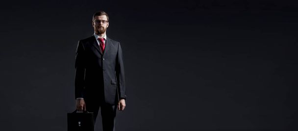 Businessman with briefcase standing over dark dramatic background. Business and office, concept. - Φωτογραφία, εικόνα