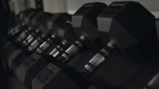 黒のフィットネス ダンベルのクローズ アップ。フィットネス センターには、重みとフィットネス トレーニングのために新しいダンベル。トレーニング機器の概念 - 映像、動画