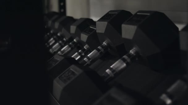 黒のフィットネス ダンベルのクローズ アップ。フィットネス センターには、重みとフィットネス トレーニングのために新しいダンベル。トレーニング機器の概念 - 映像、動画