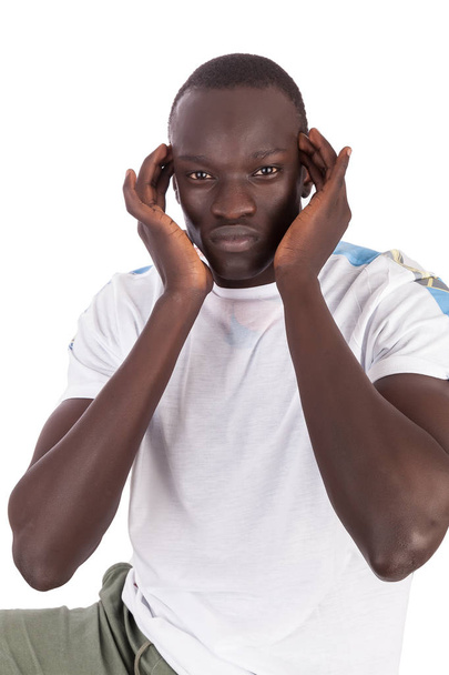 Joven hombre sudanés guapo cara a cámara manos a las sienes que indican dolor de cabeza o alivio de estrés en formato de retrato con espacio de copia para las emociones aisladas en el fondo blanco. Doloroso.
 - Foto, Imagen