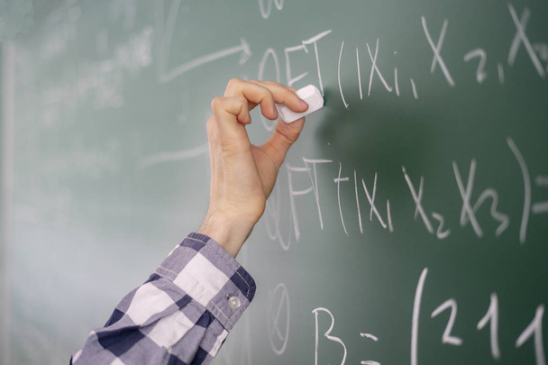 persons hand hold chalk and write mathematic calculations on a board b - Foto, Imagen