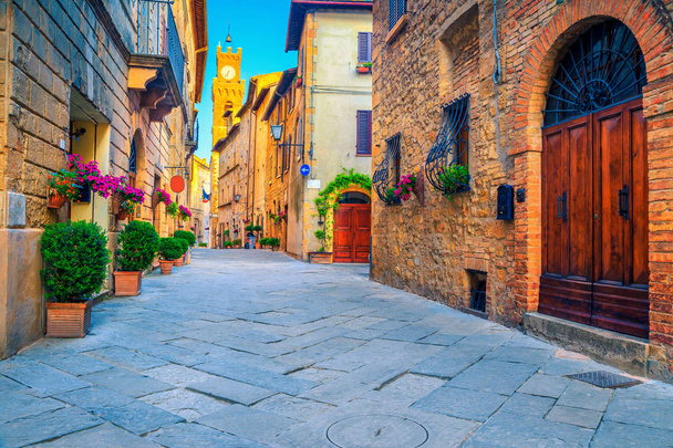 壮大な伝統的なトスカーナ ストリート ビュー。見事な中世の石造りの家と花の入り口、ピエンツァ、トスカーナ、イタリア、ヨーロッパで舗装された通り - 写真・画像