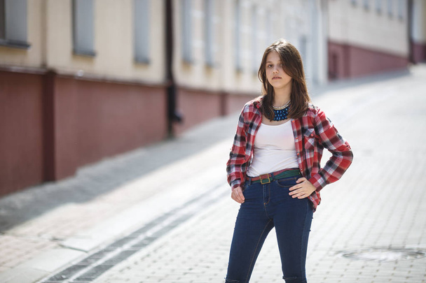 close up portrait of beautiful girl teenager in bright plaid shirt in urban street background - Zdjęcie, obraz