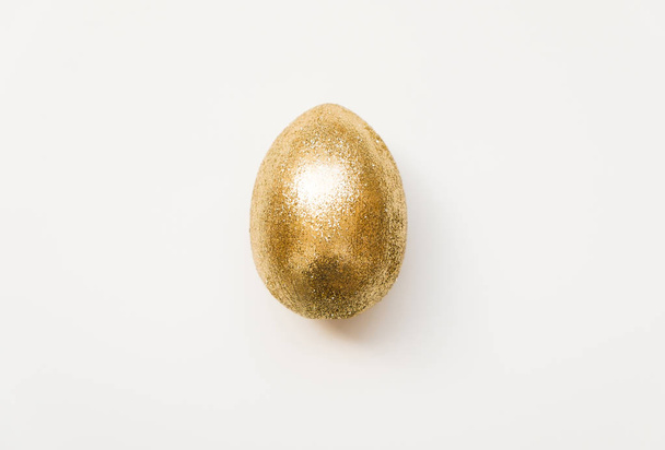 Easter golden glitter egg  isolated on white background. Minimal easter concept. Happy Easter card. Top view, flatlay.   - Photo, Image
