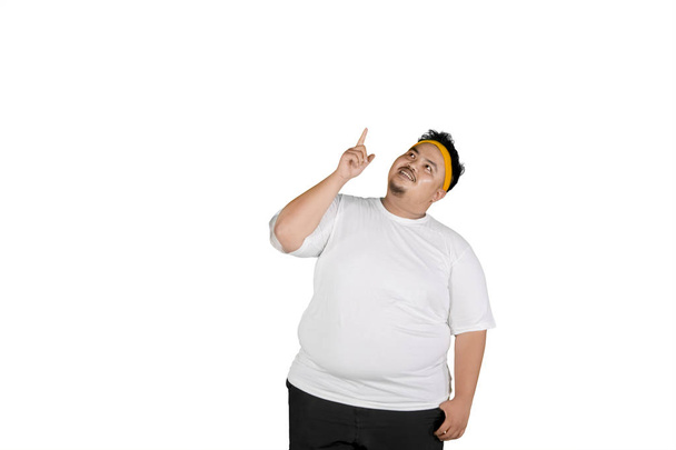 Portrait of an obese man wearing sportswear while thinking something, isolated on white background - Photo, image