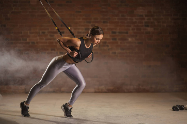 Fitness woman workout on TRX straps in gym. Crossfit style. Training TRX. - Zdjęcie, obraz