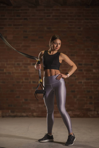 Fitness woman workout on TRX straps in gym. Crossfit style. Training TRX. - Foto, Bild