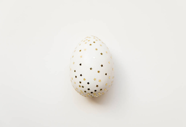 Easter white egg with glitter stars  isolated on white background. Minimal easter concept. Top view, flatlay.   - Фото, изображение