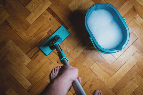 Afvegen vuile houten vloer door natte wisser mop, huishoudelijk werk. Man schoonmaken van het huis. TopView - Foto, afbeelding