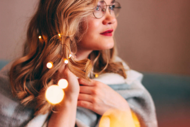 Young charming blonde woman in glasses with lights in her hair, romantic atmospheric photo about dreams, blurred focus - Фото, изображение