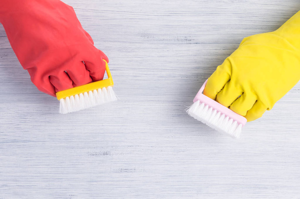 hands in rubber yellow and red gloves washed with brushes light gray wooden floor - Photo, image