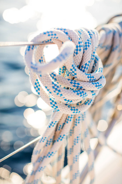 Detail of a mooring rope placed on sailing boat yacht desk. Leasure activities and extreme sport. Low depth of focus. - Фото, изображение