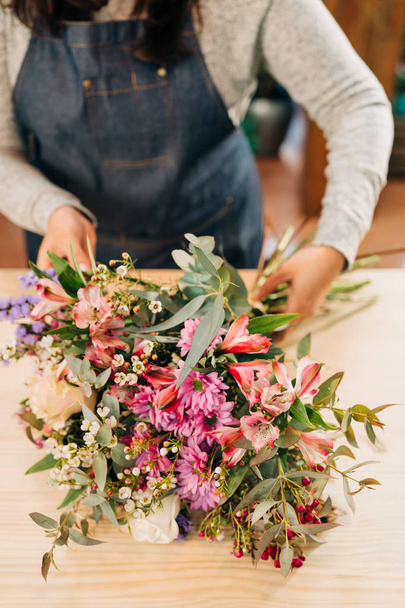 Woman florist hace bouquet de flores y envoltura en papel de embalaje. - Foto, Imagen