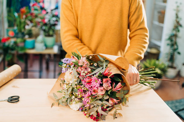 Man florist makes flowers bouquet  and wrapping in pack paper - Photo, Image