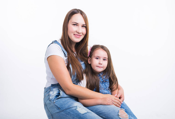 Family, children and parenthood concept - Young woman with her little cute child on white background. Mom with daughter isolated. - Fotografie, Obrázek