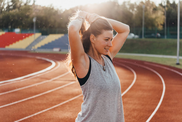 A young beautiful woman is getting ready for jogging of exercising at a stadium running track. - Fotoğraf, Görsel