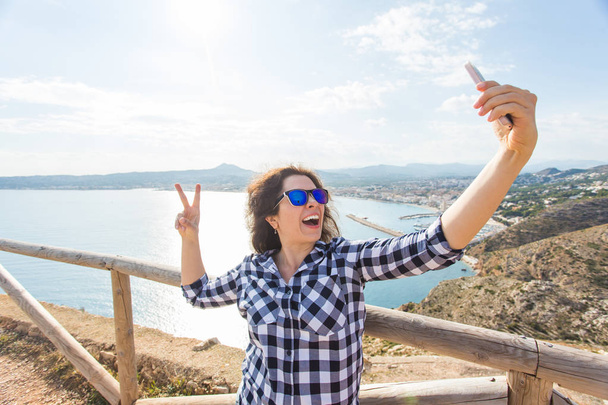 Vakantie-, vakantie- en reisinformatie concept - Happy jonge vrouw selfie overname prachtige landschap - Foto, afbeelding