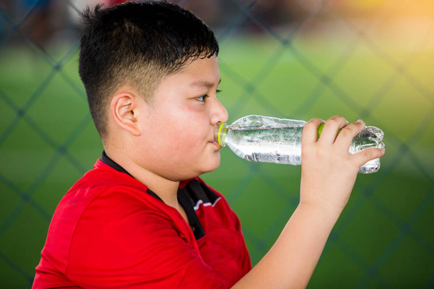 Portrait d'un adolescent buvant de l'eau sur un terrain de soccer
 - Photo, image