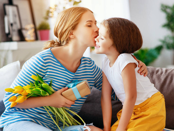 Hyvää äitienpäivää! lapsi tytär onnittelee äitiä ja antaa kukkakimpun tulppaanille ja gifille
 - Valokuva, kuva