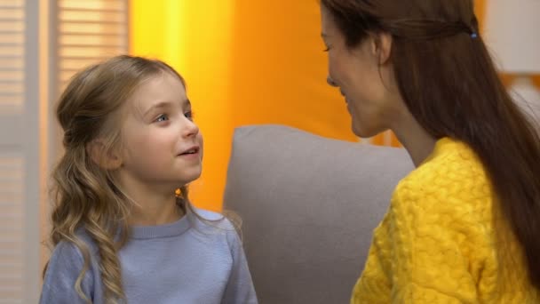 Pretty preschool girl telling smiling mom funny story, both laughing and hugging - Felvétel, videó