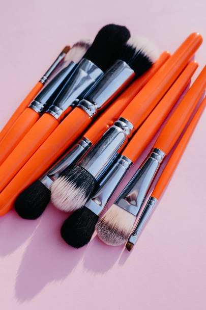 Σετ πινέλα μακιγιάζ σε πορτοκαλί χρώμα σε ροζ φόντο - Φωτογραφία, εικόνα