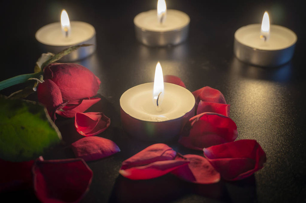 Cztery świece herbaty i czerwone płatki róż w ciemności z płytkiej głębi ostrości - Zdjęcie, obraz