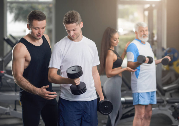 Gym trainers helping people to work out. - Foto, Bild