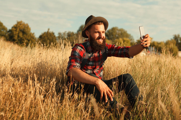 Bearded traveler taking selfie in field - Foto, Imagem