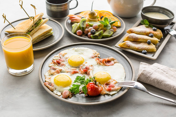 Πρωινό, ομελέτα, φρούτα, τηγανίτες, χυμός πορτοκαλιού, τσάι και σάντουιτς - Φωτογραφία, εικόνα
