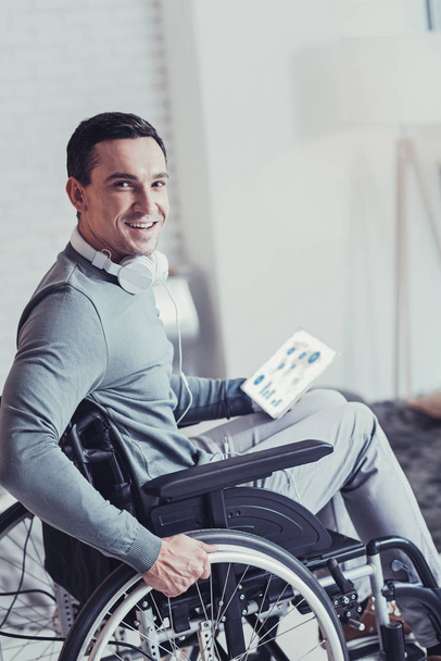 Iloinen komea mies istuu pyörätuolissa
 - Valokuva, kuva