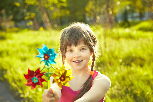 cheerful little girl playing with pinwheel in summer park - Fotografie, Obrázek